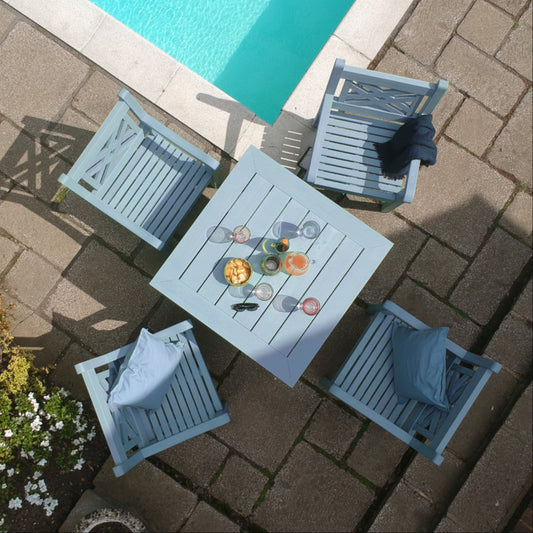 Outdoor patio set with table and chairs by a pool