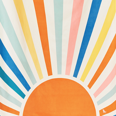 A Dock & Bay quick-dry beach towel with a colorful geometric sunrise pattern, displayed both open and rolled up in its packaging.