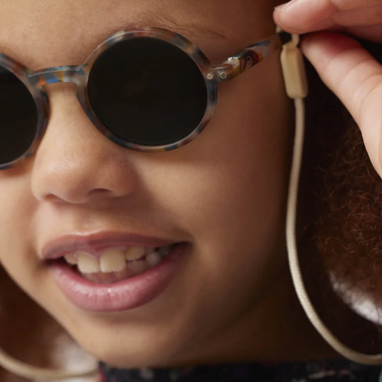 Close-up of a child wearing round sunglasses with a blurred background