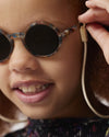 Close-up of a child wearing round sunglasses with a blurred background