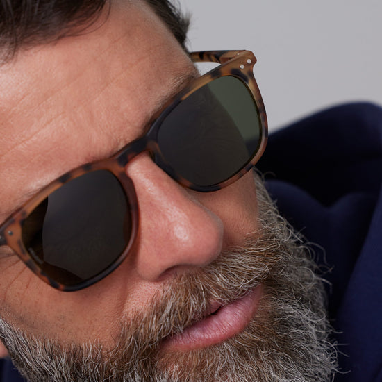 Close-up of a person wearing sunglasses with a neutral background